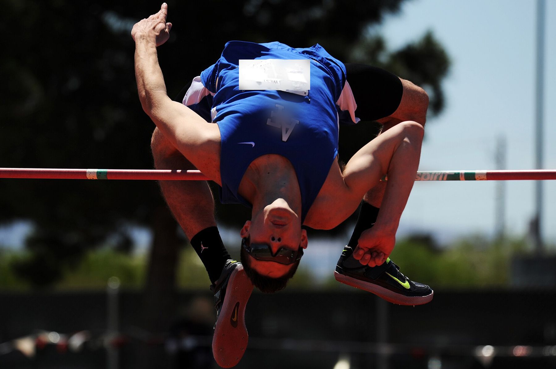 An Apex high jumper arches over the bar against the sky