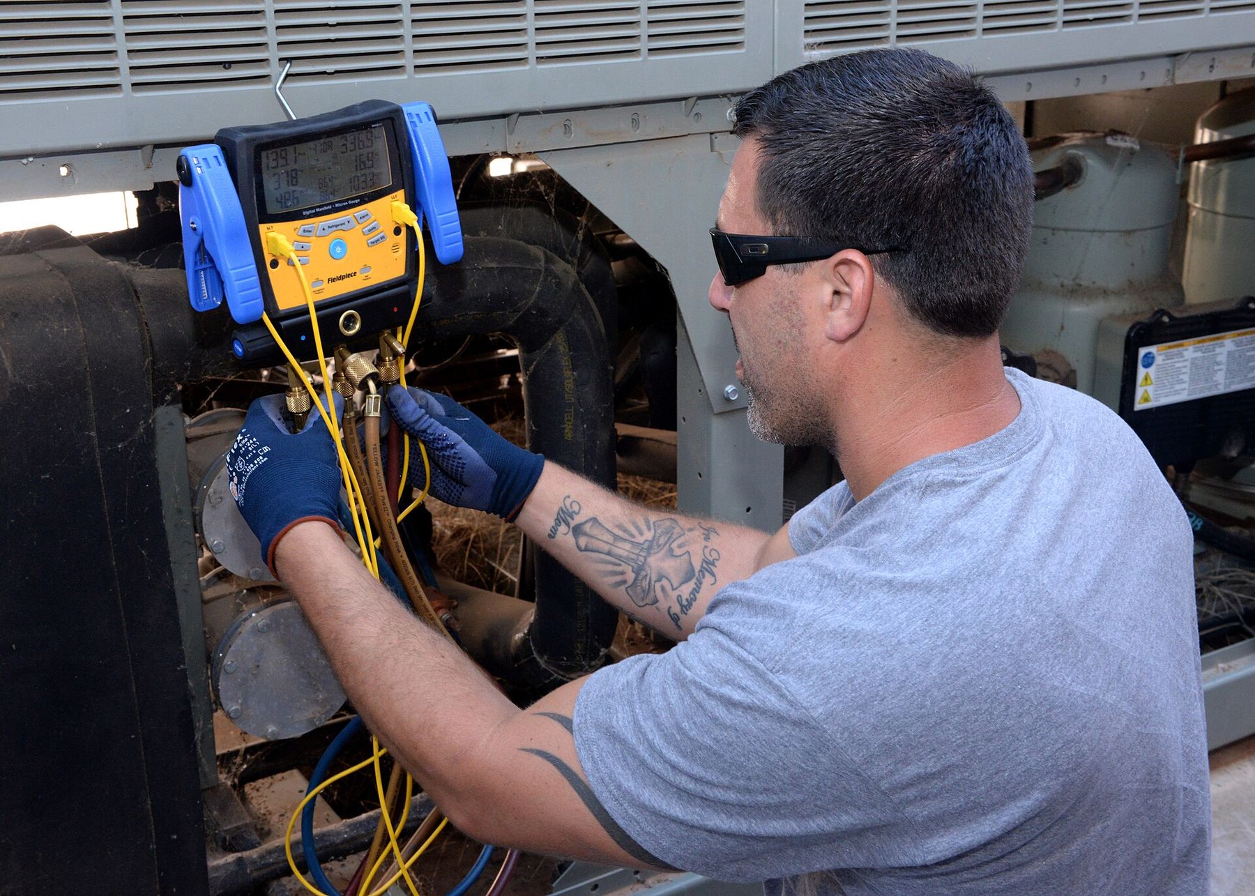 A Ridgeline technician checks refrigerant pressures on an outdoor AC unit